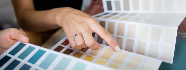 A person looking at several paint swatches on a table